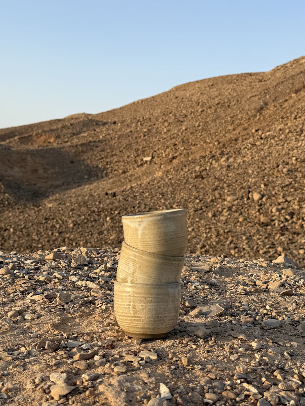 Three stacked ceramic cups on rocky desert ground