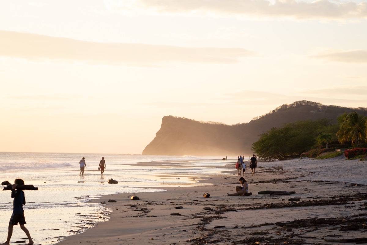People walking along the beach at sunset