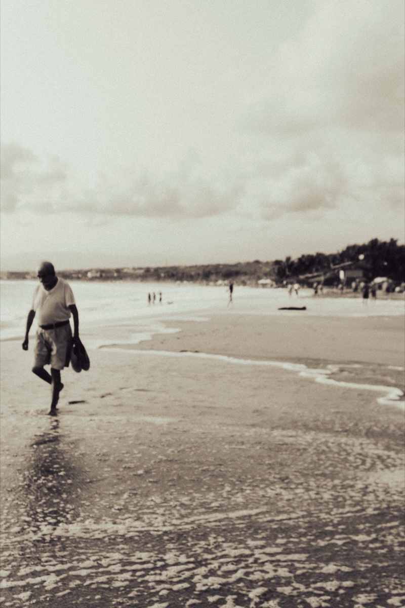 Sepia-toned photo of a man walking along the beach