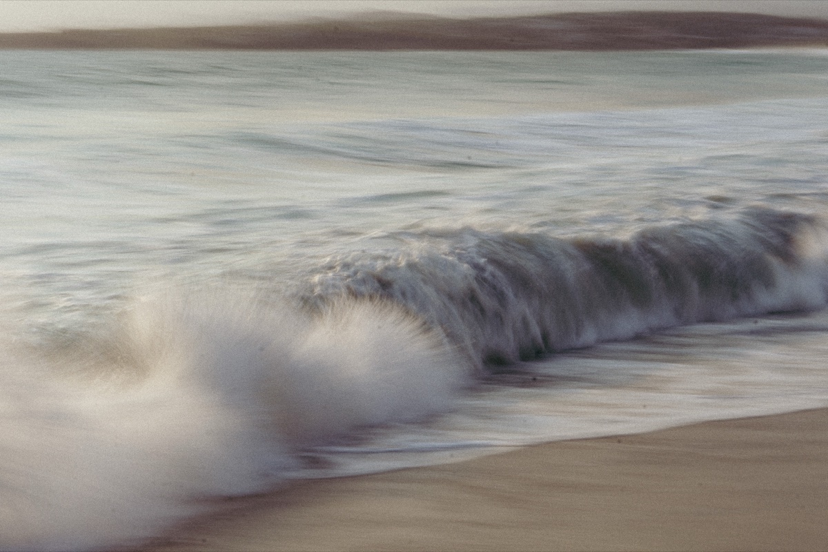 Long-exposure shot of a wave breaking on the shore