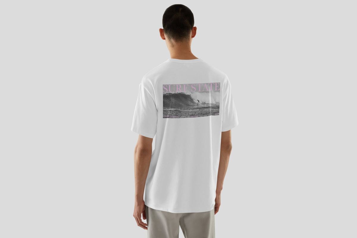 White t-shirt mockup with a Surf State graphic printed on the back, featuring a black-and-white surf photo
